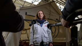 Kvinna i Läkare Utan Gränser-kläder blir intervjuad med två mikrofoner riktad mot sig.