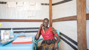 hälsoarbetaren Margaret Abuk sitter vid ett bord på en hälsomottagning i flyktinglägret Majar Aher i Sydsudan