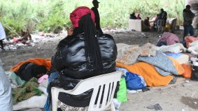 Kvinna med svart jacka och rygg mot kameran, framför henne massa färglada täcken. 