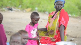 Kvinna sitter på marken tillsammans med sitt barn. 
