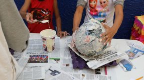 Två barn använder limmar papperstidningar på en uppblåst ballong.