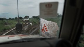 bild tagen genom den smutsiga vindrutan på en bil, framför en annan bil på en lerig väg