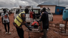 hälsoarbetare kör en kvinna i koma på en bår till en väntande ambulans