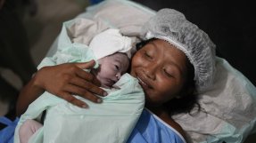 En nybliven mamma håller i sitt nyfödda barn på sjukhuset.