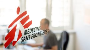 Logotyp med skymtande person bakom.