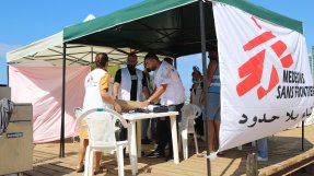 Medarbetare vid en mobil klinik på en strand.