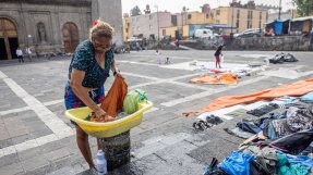 En kvinna tvättar kläder i en balja på ett torg i Mexico City.