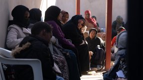 En grupp kvinnor sitter väntandes i en lång kö.