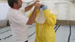 En medarbetare från Läkare Utan Gränser tar på sig skyddskläder vid en ebolainsats i Uganda 2012.