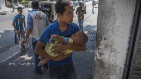 En ung man bär in ett barn på vår eftervårdsklinik i Gaza. FOTO: Yann Libessart