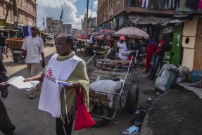 Hälsoinformatören Catherine Ndunge delar ut flyers om kliniken på en av Mathares myllrande gator. 