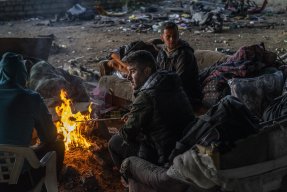 En grupp migranter och asylsökande i Bosnien värmer sig vid en öppen eld
