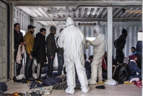 Två personer i skyddsdräkt kontrollerar migranter ombord Ocean Viking