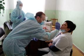 En man tar en halsprov på en sittande kvinna.