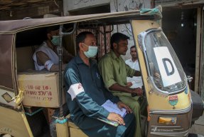 Hälsoinformatören Munir Hussain delar ut munskydd i Karachi, Pakistan, för att stoppa spridningen av covid-19.
