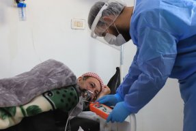 En sjuksköterska tittar till en patient med misstänkt covid-19 på sjukhuset i Idlib, Syrien.