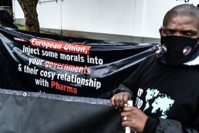 En man står vid ett plakat vid en demonstration för rättvis fördelning av covidvaccin i Sydafrika.