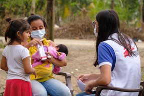 En anställd från Läkare Utan Gränser samtalar med en kvinna och hennes två barn i Choloma, Honduras.