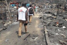 Två personer från Läkare Utan Gränser går genom det nedbrunna lägret i Cox,s Bazar, Bangladesh.