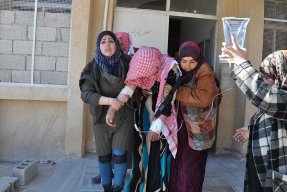 Några kvinnor stöttar en kvinna med dropp utanför en vårdcentral i Abu Qalqal, Syrien.