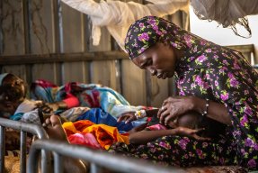 Rauda Adam Isa klappar sin dotter på pannan i en sjukhussäng på sjukhuset El Fasher, norra Darfur, Sudan.