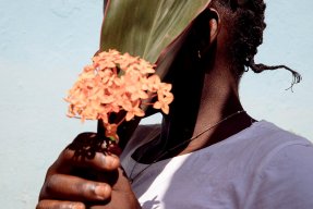 En kvinna i Centralafrikanska republiken håller en blomma framför sitt ansikte.