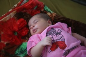 En liten bebis med rosa kläder sover på vår avdelning för nyfödda. 