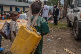 Ett barn i Sake bär på en vattendunk, efter vulkanen Nyiragongos utbrott i Kongo-Kinshasa
