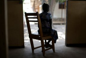 En kvinna i Centralafrikanska republiken sitter i en gungstol med ryggen mot kameran.