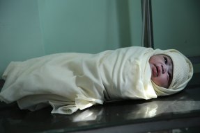 Bild på en nyfödd bebis insvept i en filt.