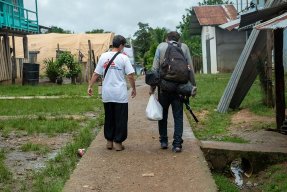 En anställd från Läkare Utan Gränser går med ryggen mot kameran bredvid en man med ryggsäck i byn Bajo Chiquito i Panama.