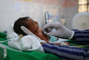 Sjukvårdspersonal lyssnar med stetoskop på en liten bebis på al Jamhouri sjukhus i Taiz City, Jemen.