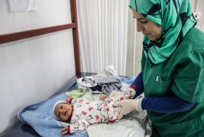 En barnmorska undersöker en nyfödd bebis i Irak.