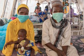 Ali, som vårdas på sjukhuset  i Magaria i Niger för malaria och uttorkning, sitter i sin mammas knä på en säng.