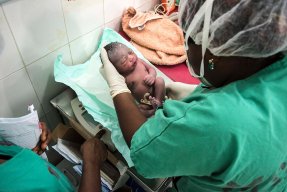 En nyfödd bebis ligger i händerna på sjukvårdspersonal på Läkare Utan Gränsers mödravårds- och förlossningsklinik  i Jahun, norra Nigeria.