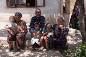 Surayo sitter med sina barn, sina föräldrar och en brorson på trappan framför deras hus i västra Tadzjikistan.
