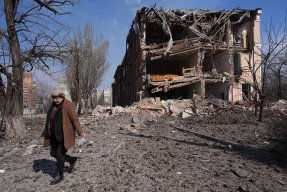En kvinna går bredvid ett hus som har förstörts av bomber i Mariupol, Ukraina.