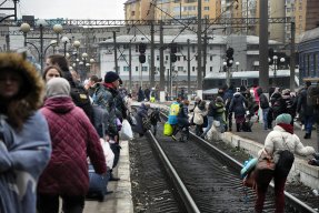 Människor med bagage korsar tågspåren i den ukrainska staden Lviv.