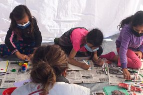 En medarbetare från Läkare Utan Gränser sitter med tre flickor och ritar i Mexiko.