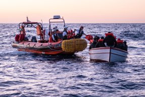 En gummibåt från Läkare Utan Gränsers sök- och räddningsfartyg Geo Barents undsätter en grupp människor från en träbåt på centrala Medelhavet.