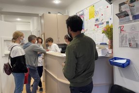 Personer står i kö vid receptionen på en vårdcentral