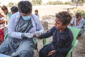 Ett Läkare Utan Gränser tekniker tar ett blodprov i fingret på ett barn.
