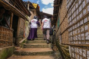 Två medarbetare med Läkare Utan Gränsers logga på ryggarna går upp för en trappa i Cox's Bazar.