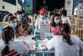 Personer sitter runt ett bord. Närmast bild sitter två personer i Läkare Utan Gränser t-shirt.