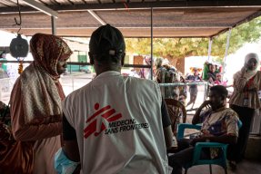 Man med Läkare Utan Gränser väst visar en blankett för en kvinna till vänster om honom