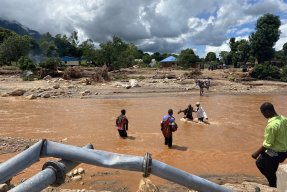 Människor korsar en flod som översvämmats