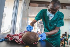 en sjuksköterska vårdar ett undernärt barn som ligger på en säng på en akutavdelning