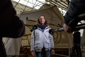 En anställd på Läkare Utan Gränser blir intervjuad av TV framför ett sjukvårdstält
