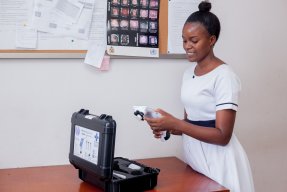 En kvinna håller i ett verktyg i handen och kollar på dess skärm.