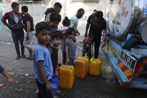 barn och vuxna köar för att hämta vatten vid en vattentank på en lastbil